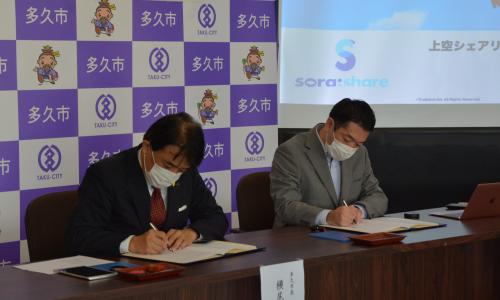 協定書にサインする増本代表取締役と横尾市長の画像