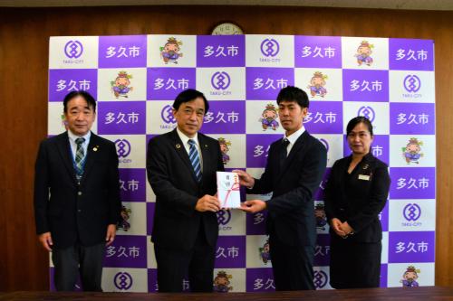 倉冨代表取締役社長(中央右)から横尾市長(中央左)へ目録が手渡されました