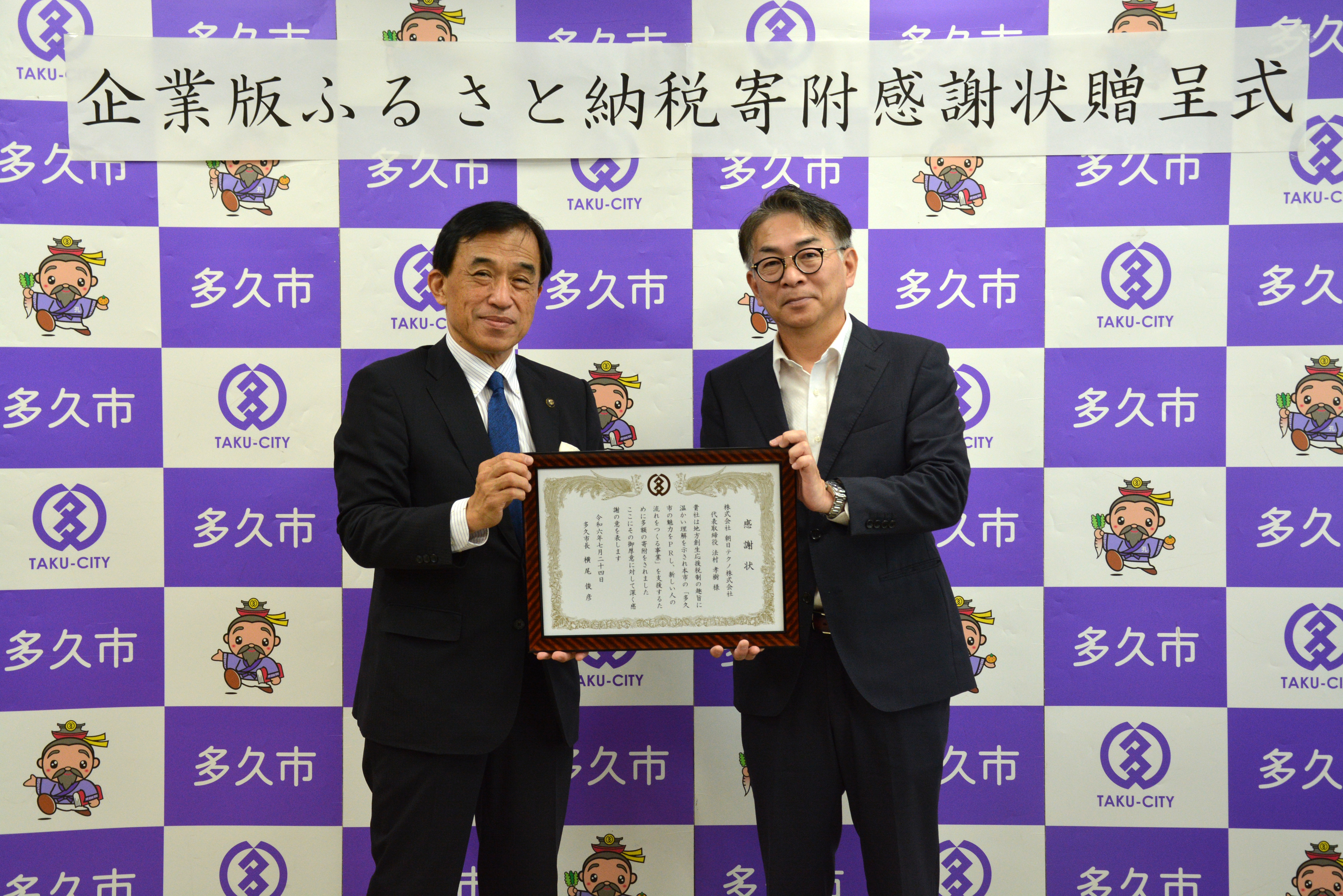 横尾俊彦市長と法村孝樹代表取締役が感謝状を持った画像
