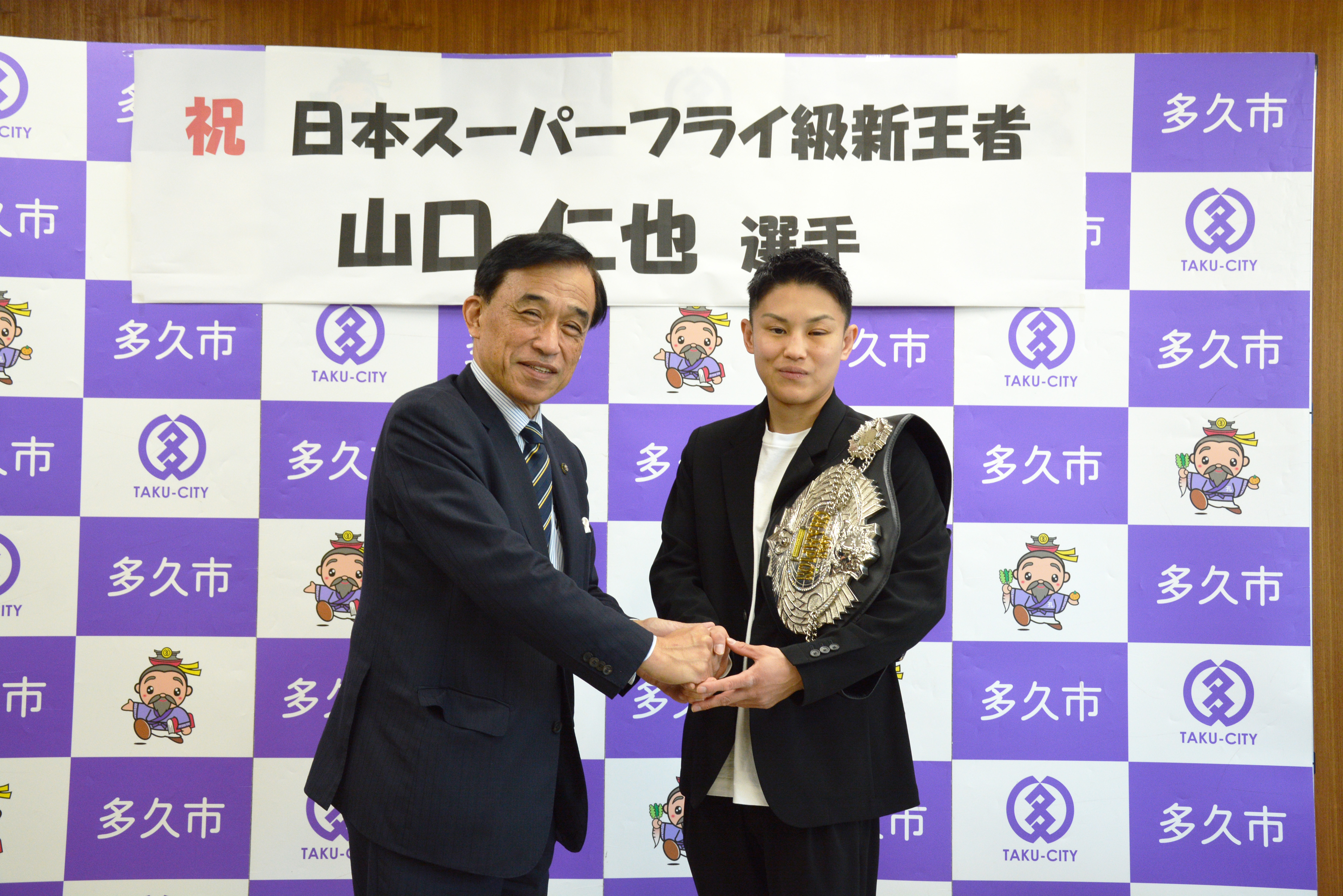 握手を交わす山口仁也選手と横尾俊彦市長