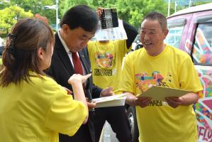 色紙にサインをする横尾市長（中央）と中村理事長（右）