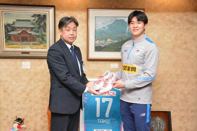 スパイクをプレゼントする安藤選手と受け取る香月市長