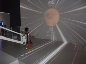 佐賀県立宇宙科学館にて子どもが他の惑星の重力を体験している写真です。