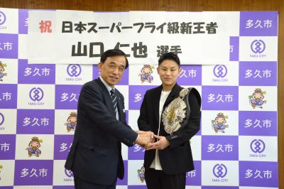 握手を交わす山口仁也選手と横尾俊彦市長