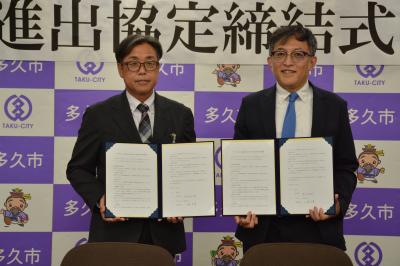 進出協定書を手にする香月市長（左）、大島予章代表取締役（右）